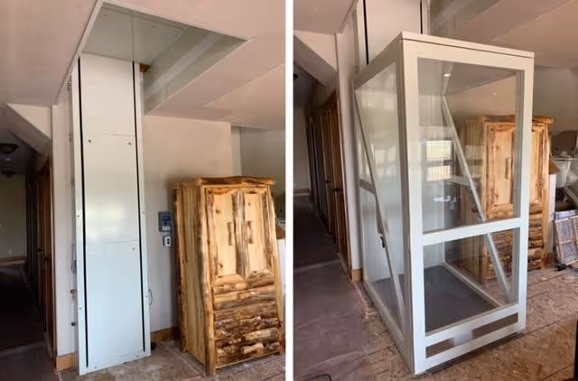 Interior construction scene with a glass-enclosed elevator and wooden cabinet.