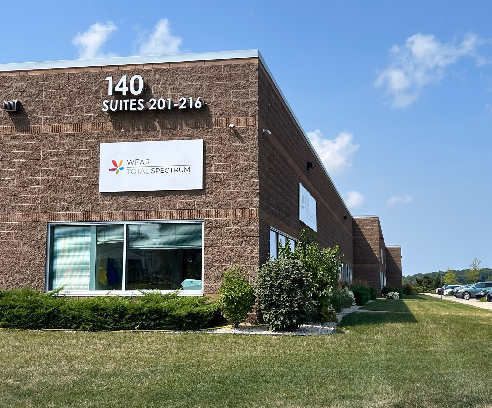 Brick commercial building exterior with 140 suites sign and Total Spectrum logo on facade.