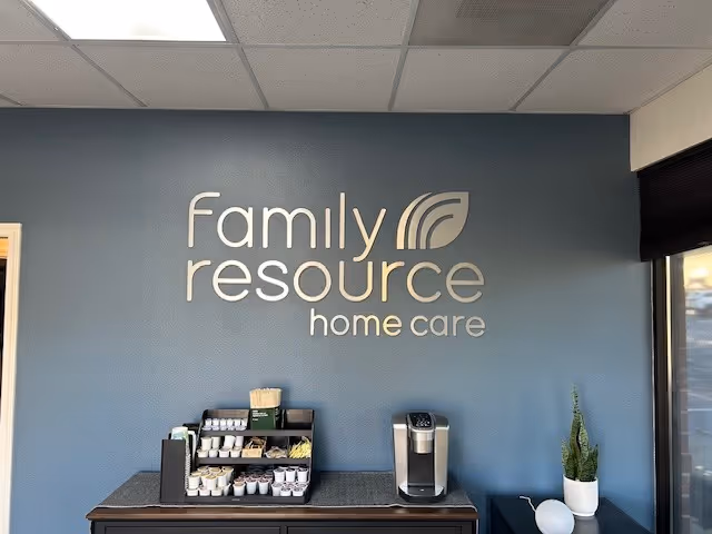 Reception area with a blue wall displaying Family Resource Home Care logo and coffee station.