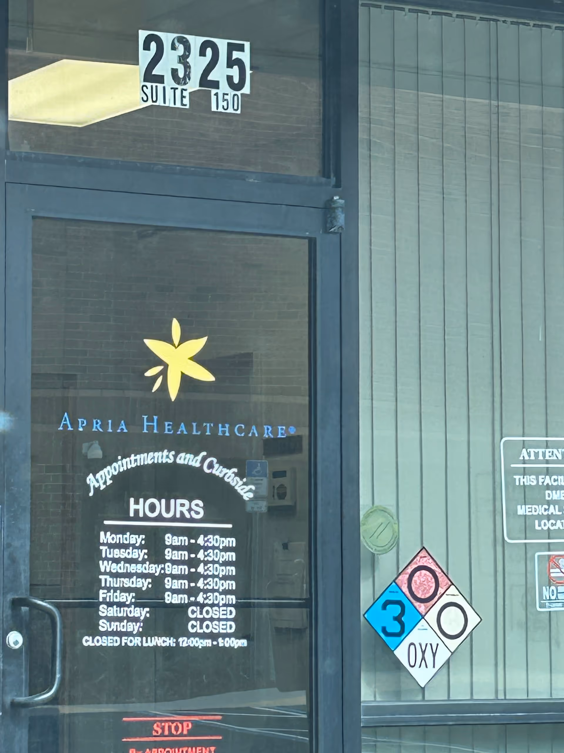 Exterior glass door displays Apria Healthcare signage, hours, and suite number.