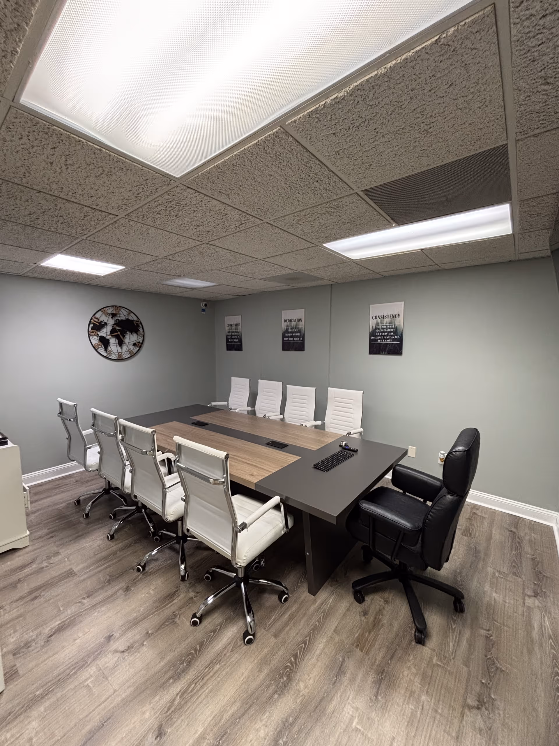 A modern conference room with a long table, white chairs, and wall posters.
