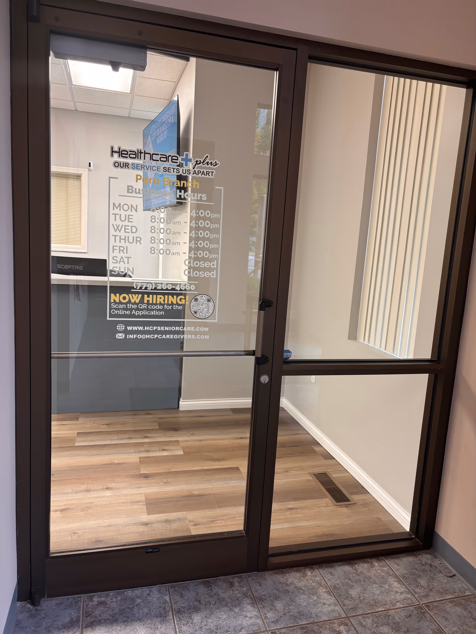 Glass entrance doors with Healthcare Plus Caregivers sign and an interior lobby area.