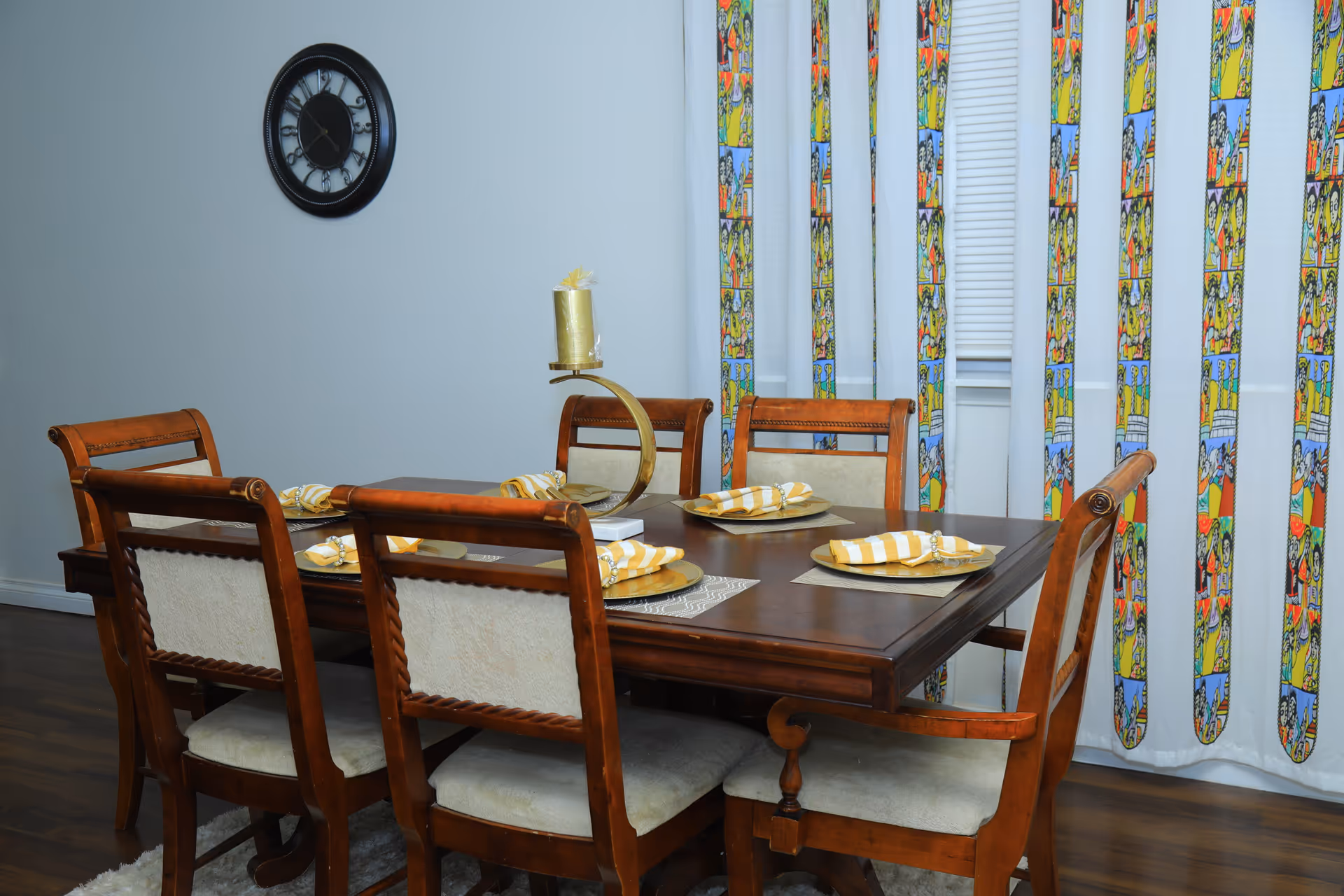 A wooden dining table with six chairs set for a meal in a colorful dining area.
