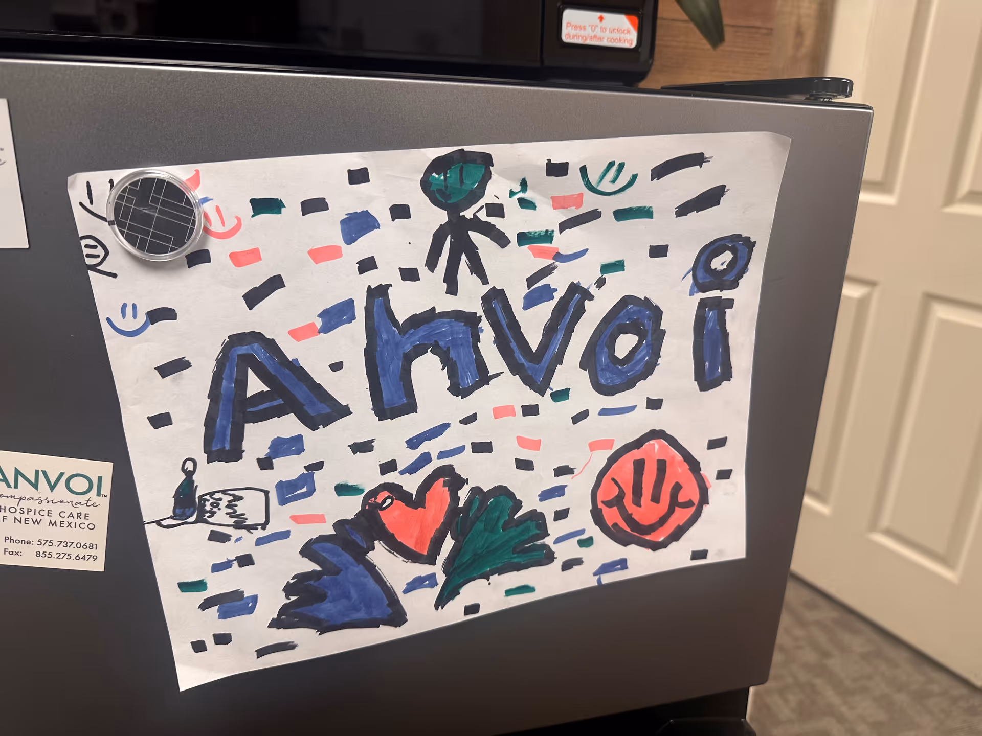 Refrigerator in a kitchen featuring a colorful child’s drawing and an Anvoi Hospice sticker.
