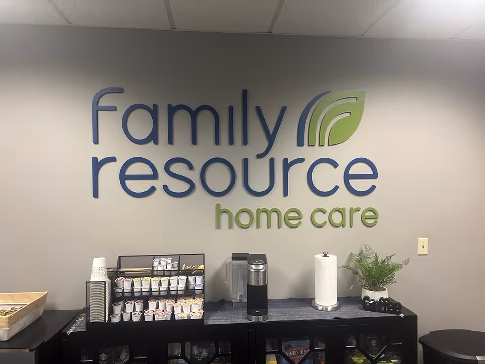 Interior wall displaying Family Resource Home Care logo beside a coffee station.