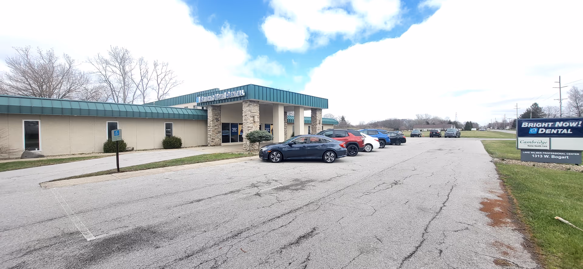 Exterior view of Cambridge Home Health Care building with green roof, stone columns, and parked cars.