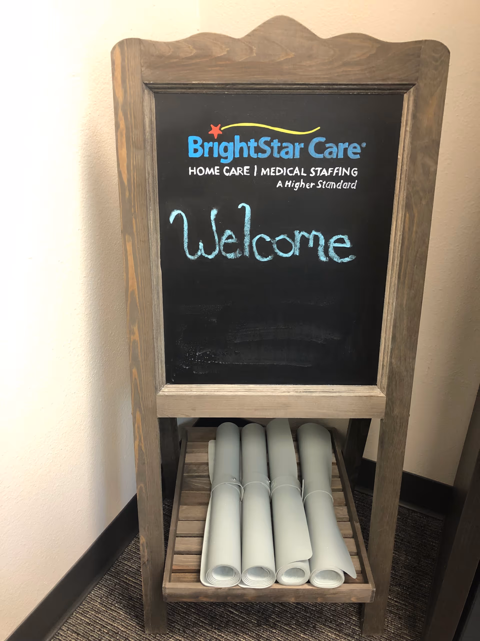 Wooden stand with a BrightStar Care chalkboard sign reading Welcome in hallway.