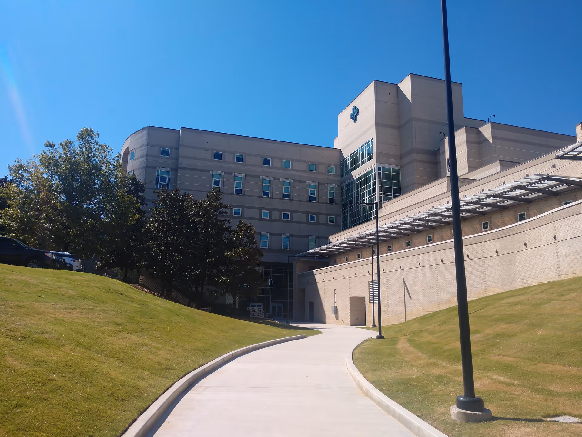 Modern medical center exterior with curved walkway and grassy lawn.