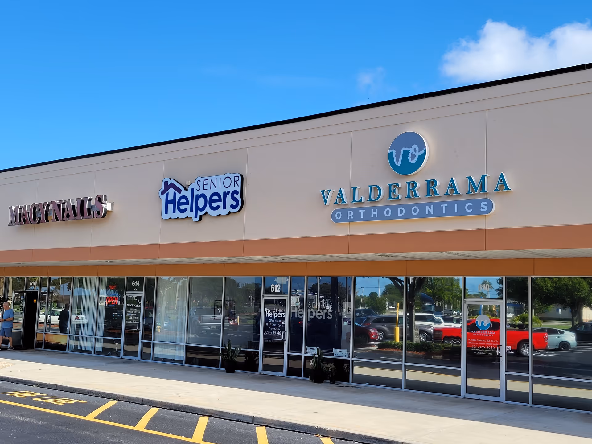 Facade of a strip mall with Senior Helpers, Macy Nails, and Valderrama Orthodontics signage.