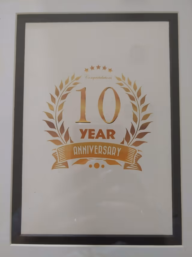 Framed 10-year anniversary poster with gold laurel design on wall
