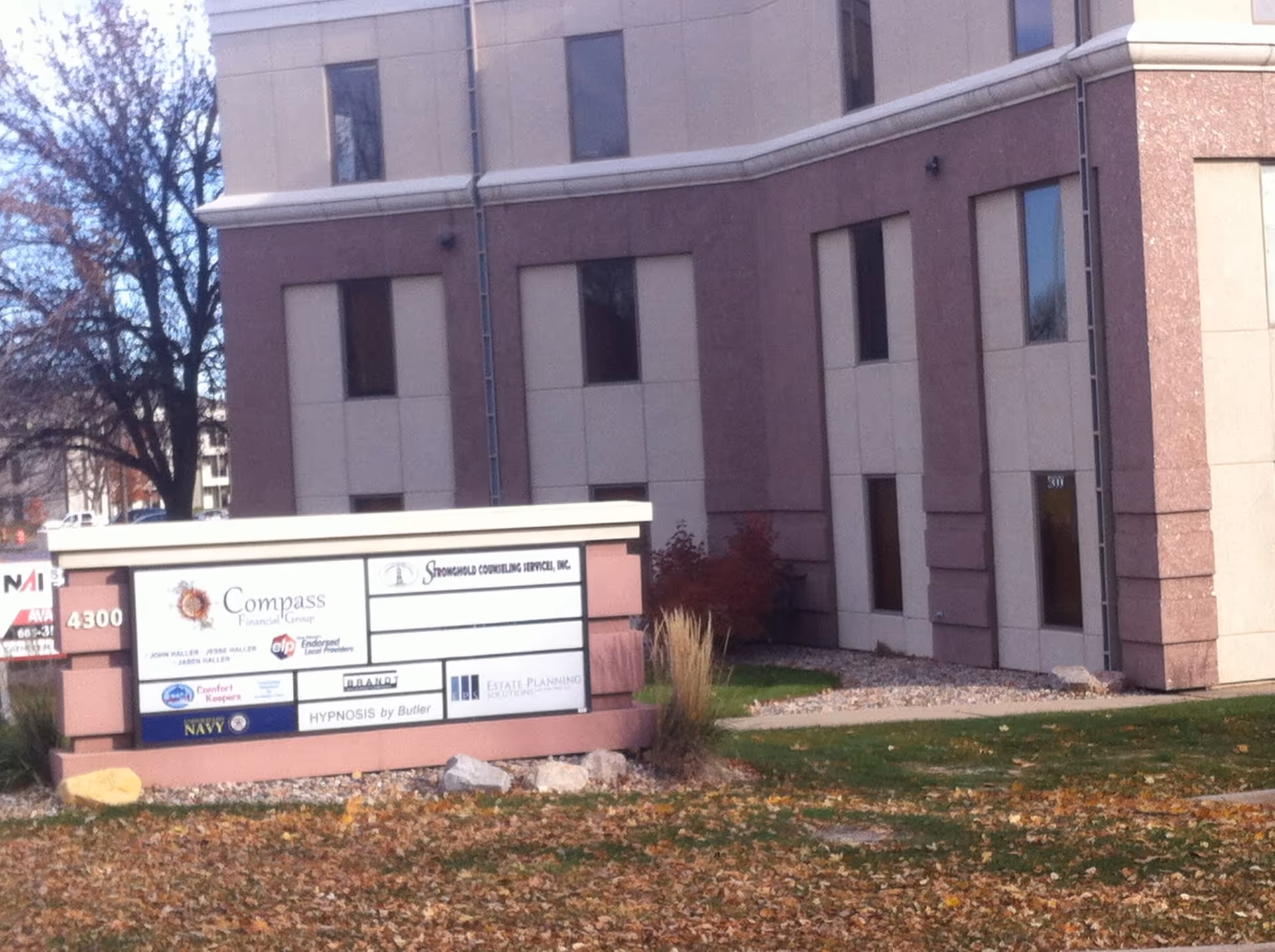 Exterior view of a multi-tenant building with a front signboard listing businesses.