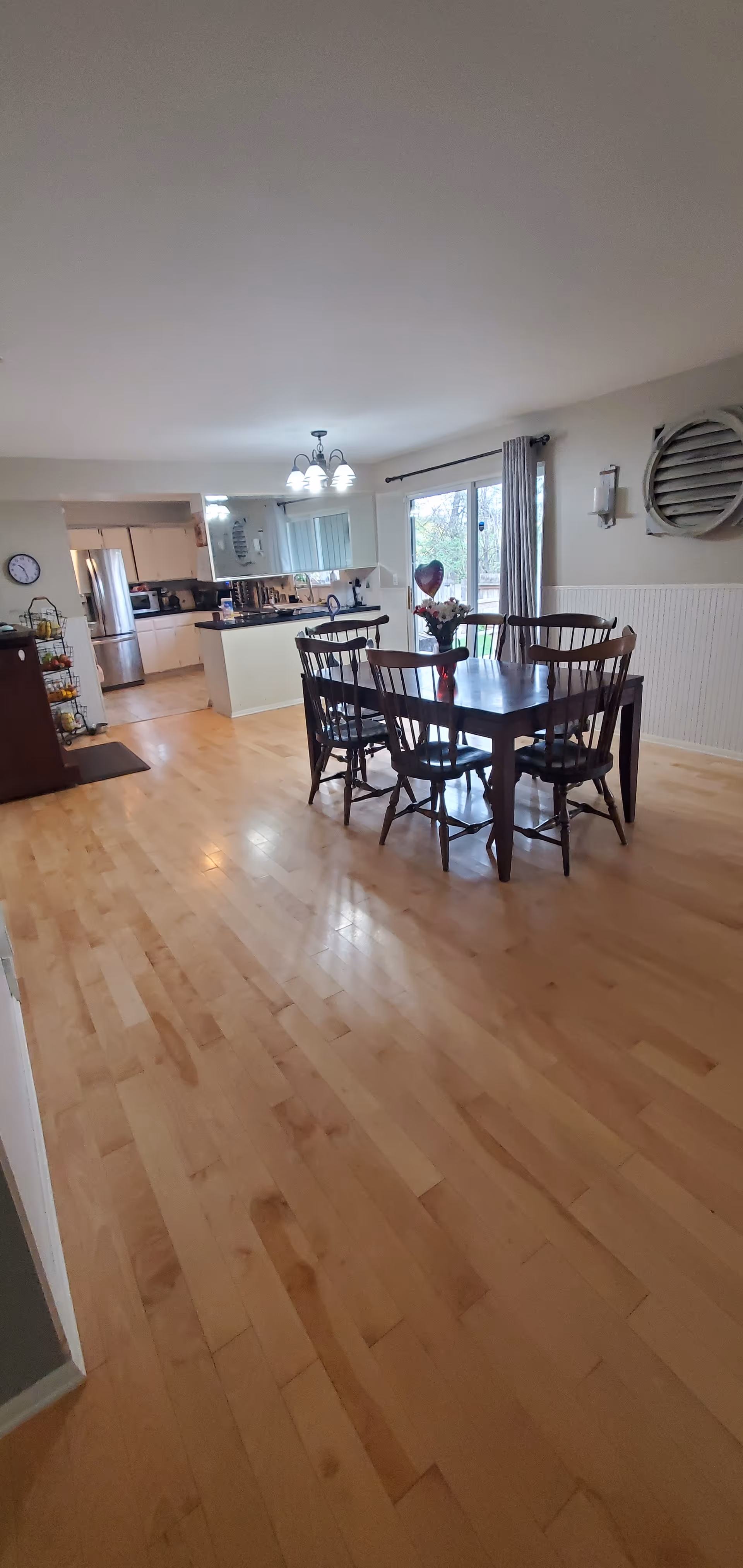 A dining area inside a senior living home with a wooden table and chairs near kitchen.