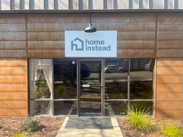 Front entrance of a Home Instead senior care facility with glass doors and a sign.