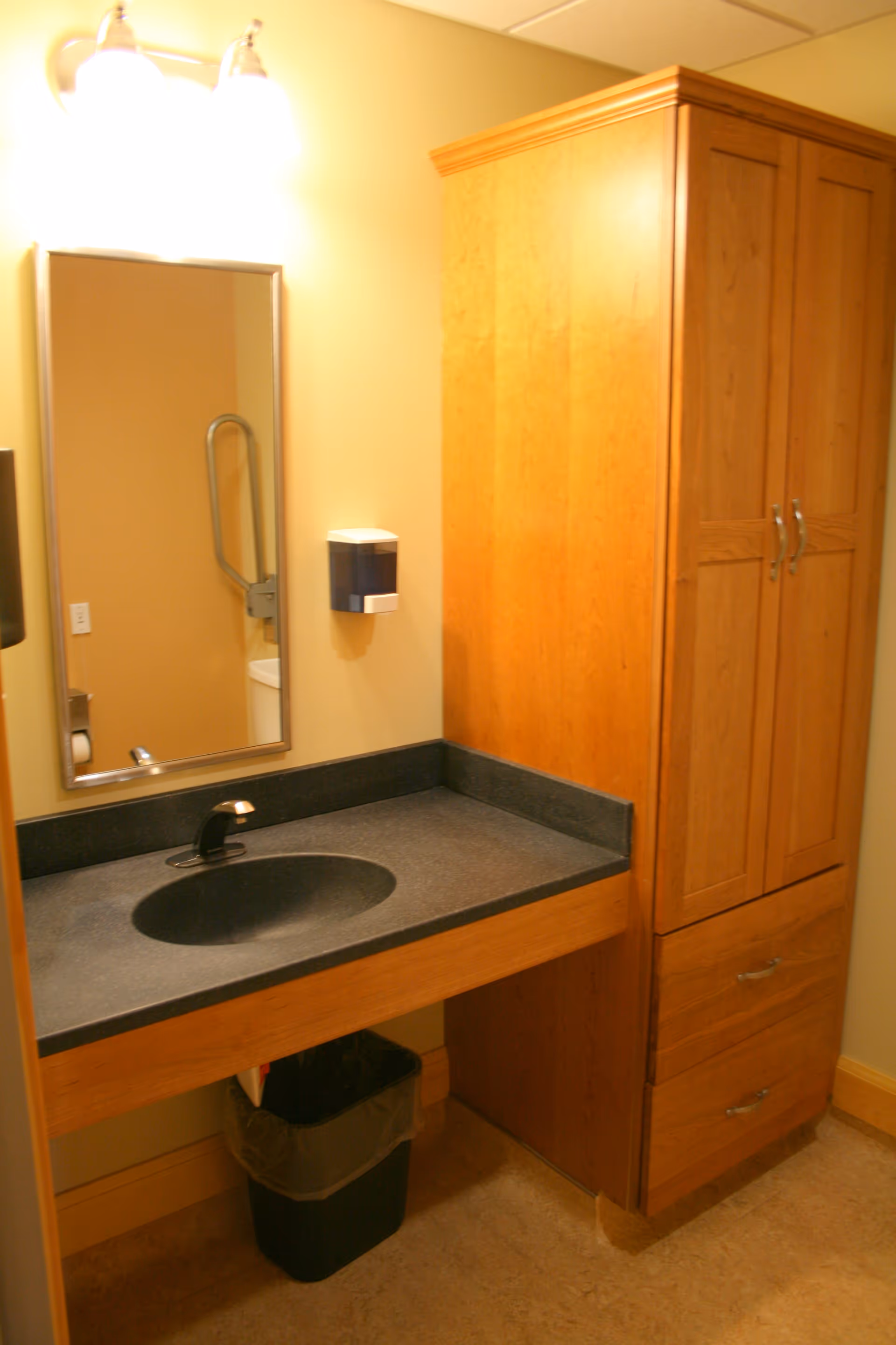 Bathroom vanity with sink, mirror, and tall wooden cabinet.