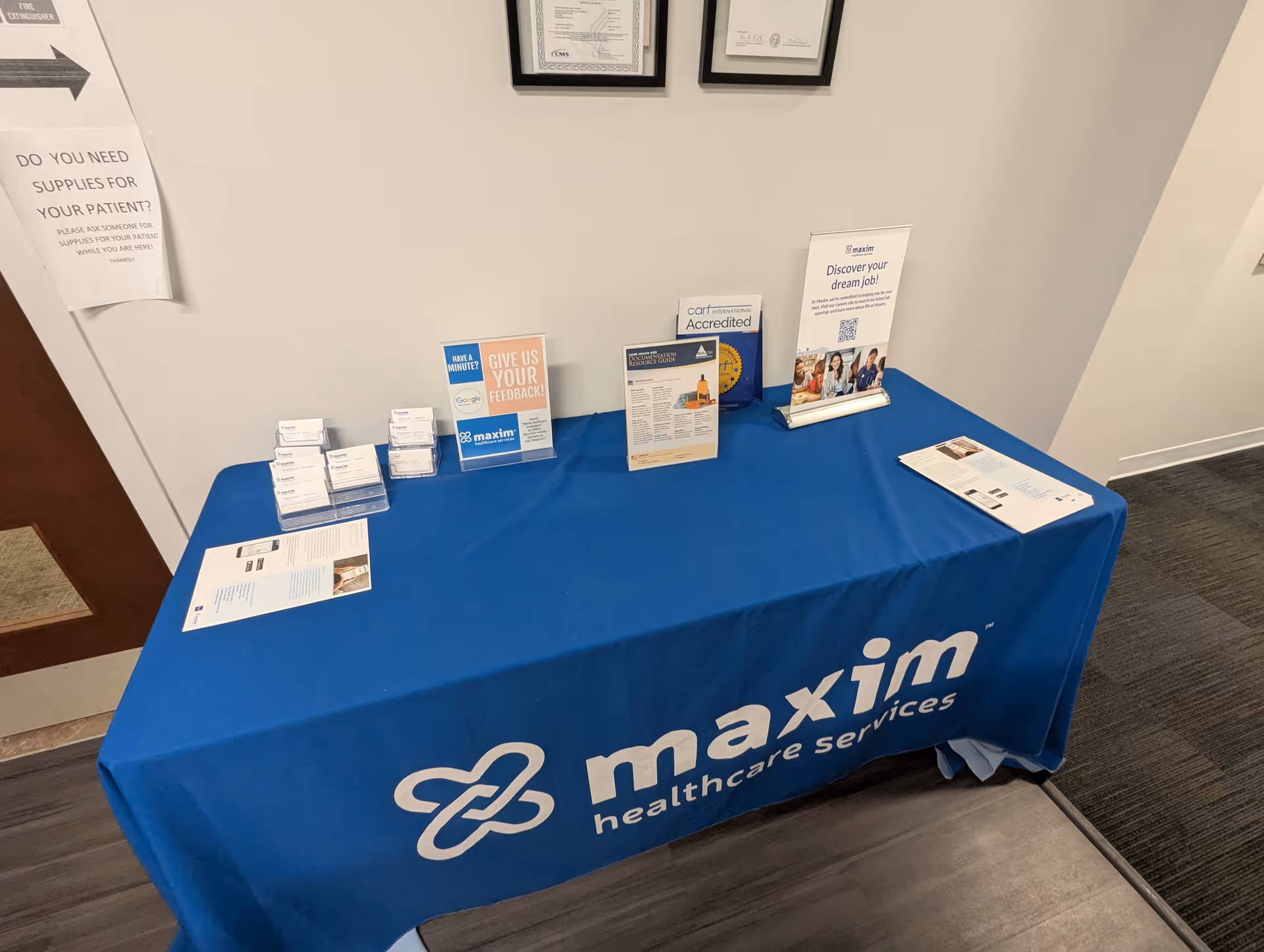 A blue Maxim Healthcare Services table with brochures in an office lobby.