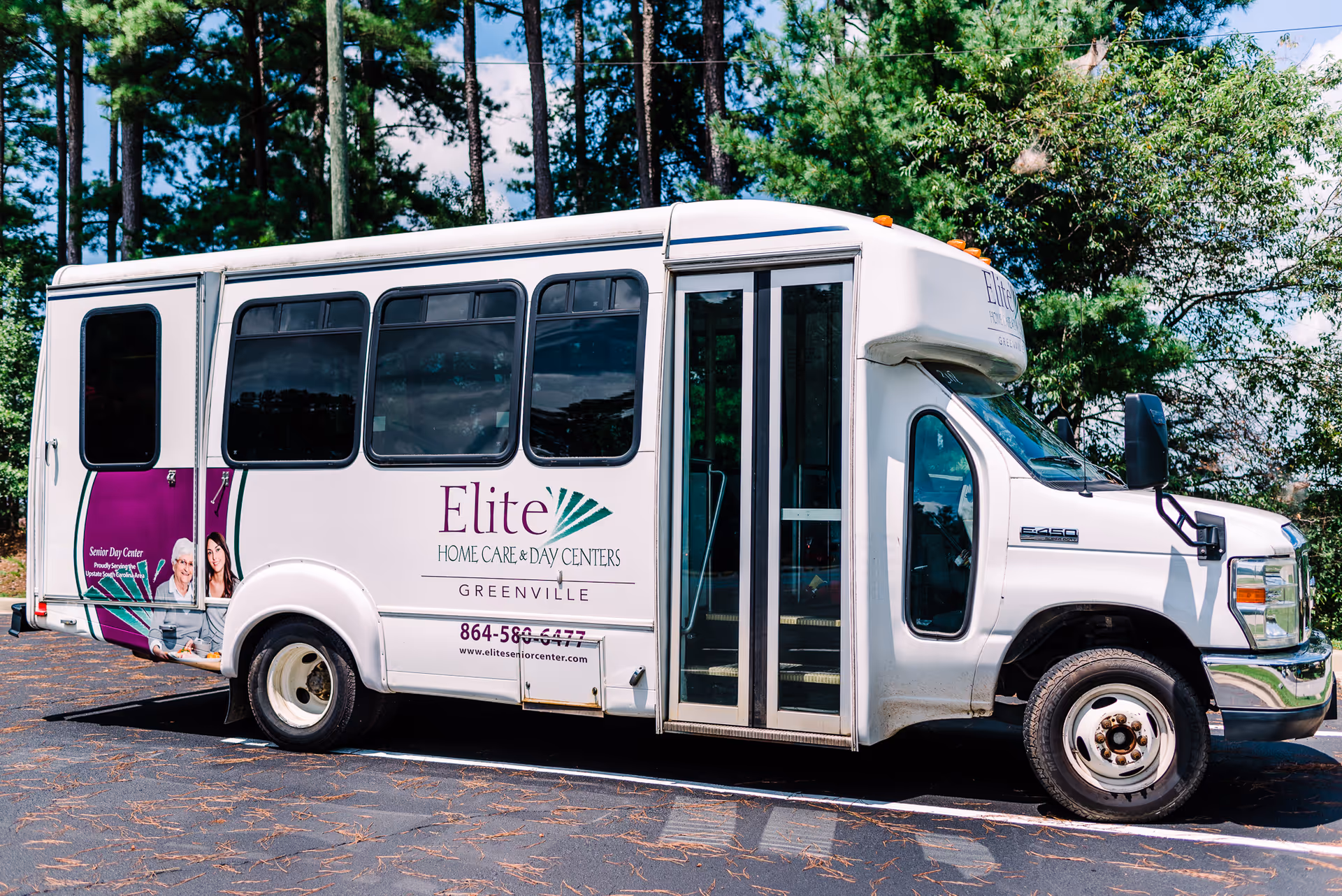 White Elite Home Care Day Centers shuttle bus parked in a lot with trees.