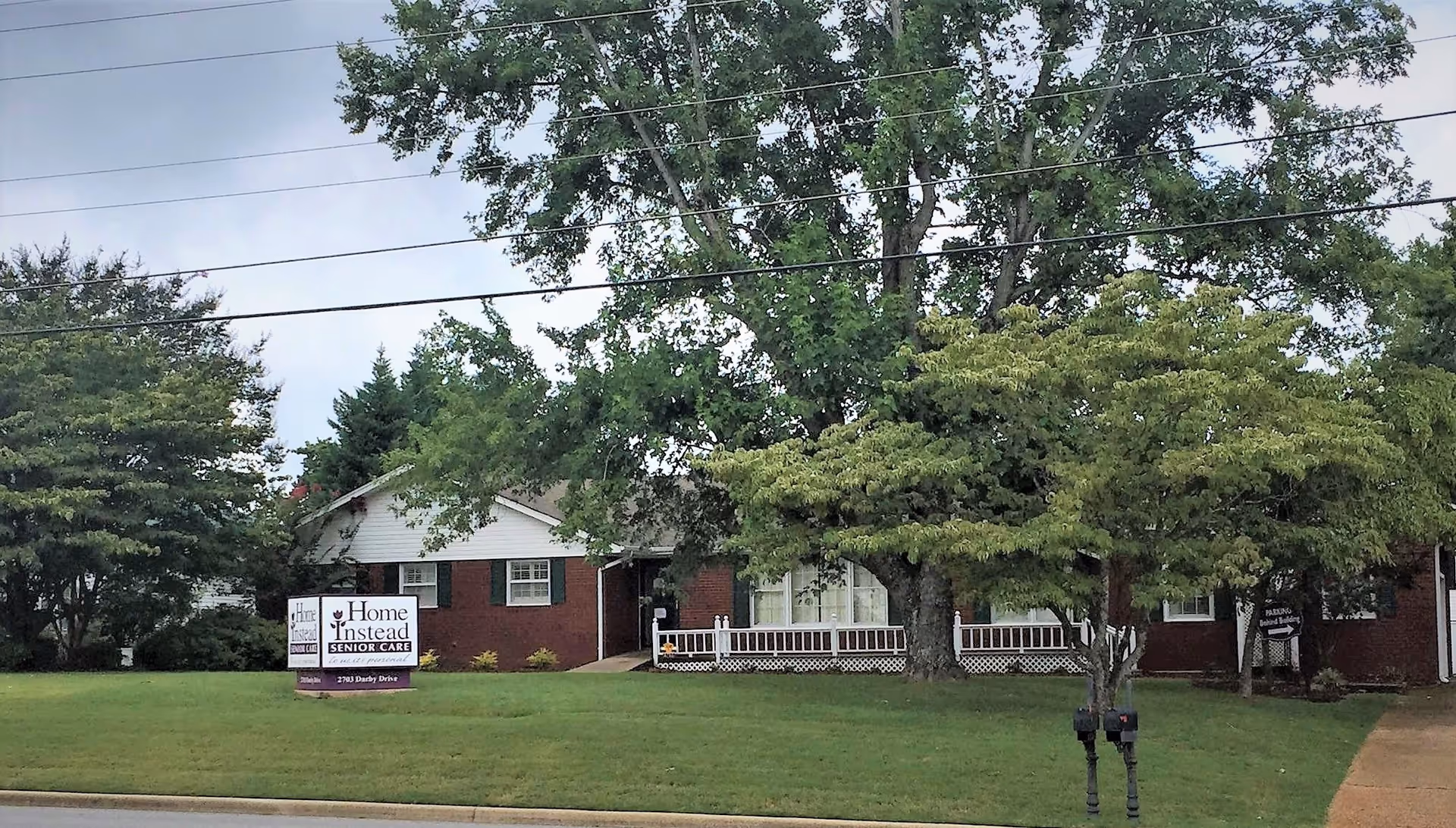Front view of Home Instead Senior Care building with sign, trees, and a green lawn.