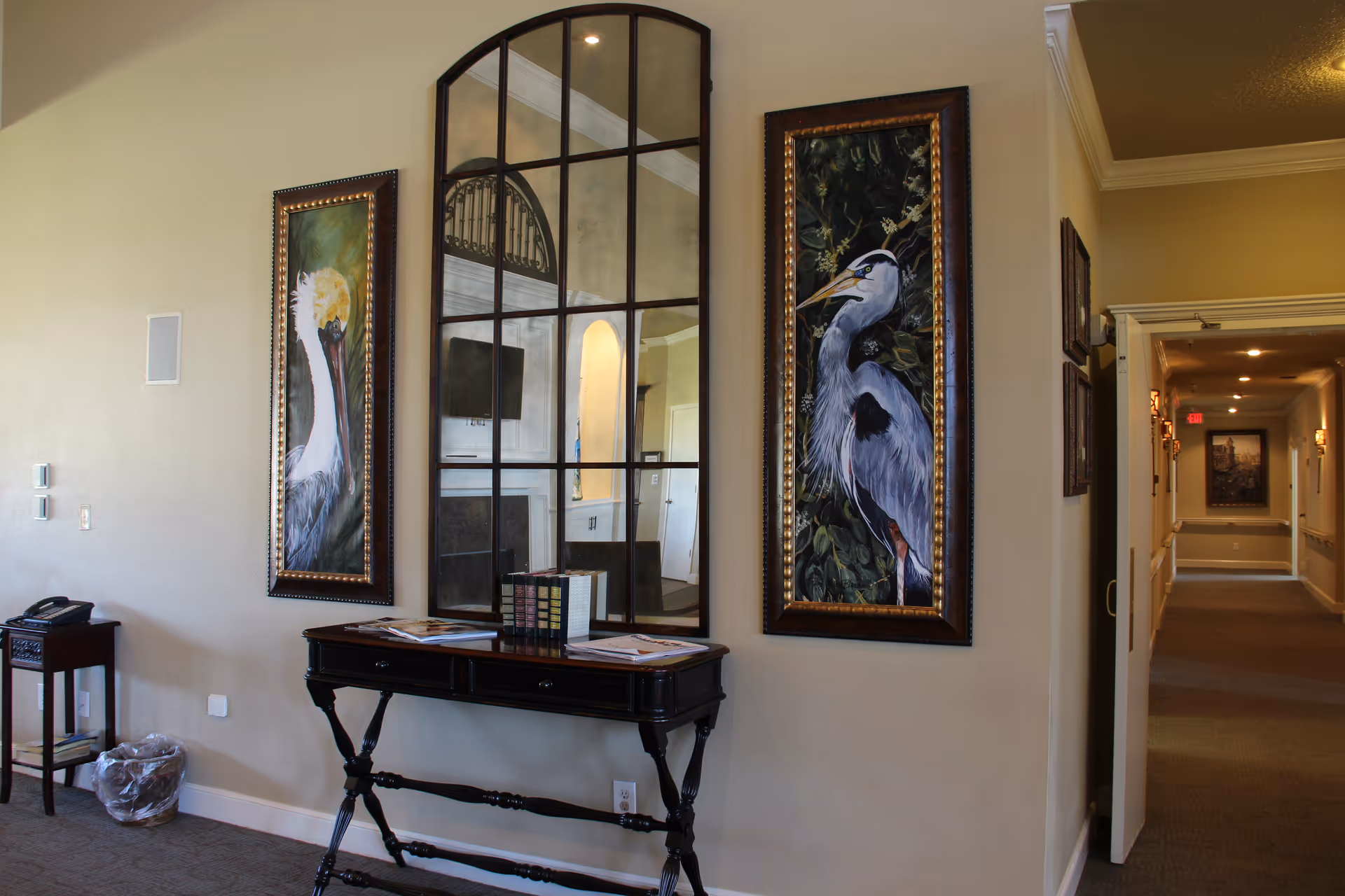 Elegant hallway interior with framed bird artwork, mirror, and a console table.