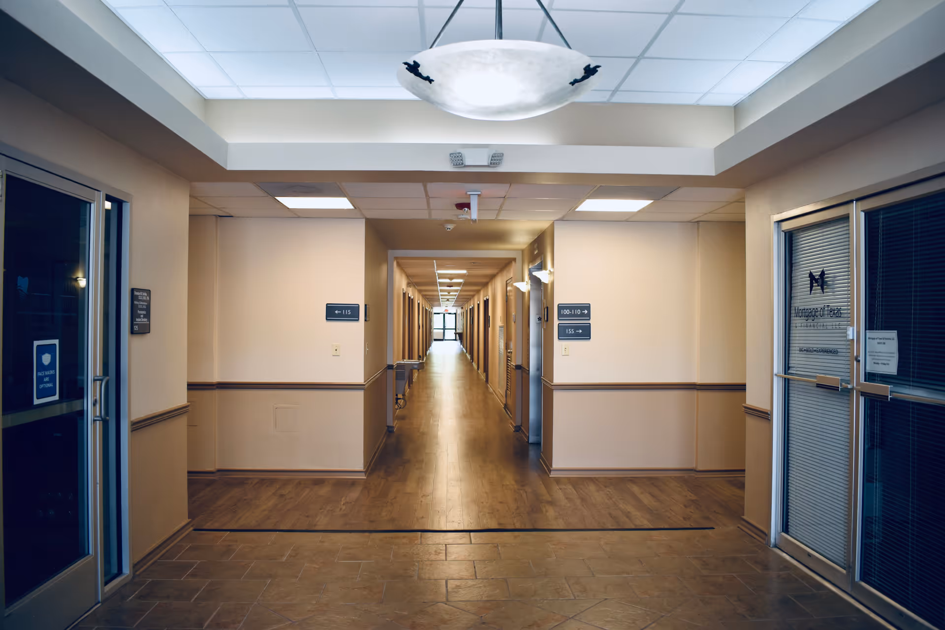 Long, well-lit corridor in a senior facility with doors along both sides.