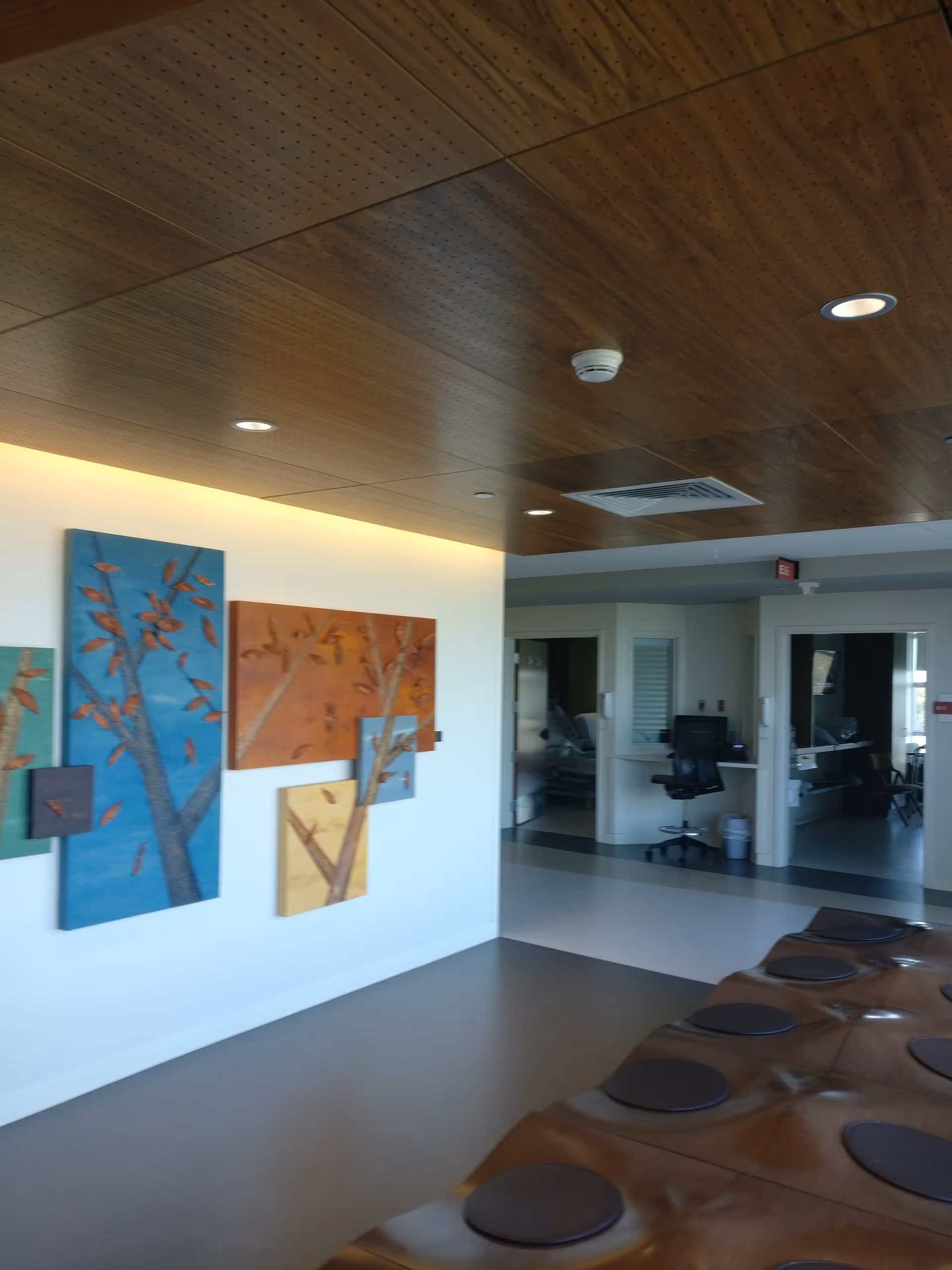 Interior hallway with wooden ceiling, wall art, and brown curved lounge seating.