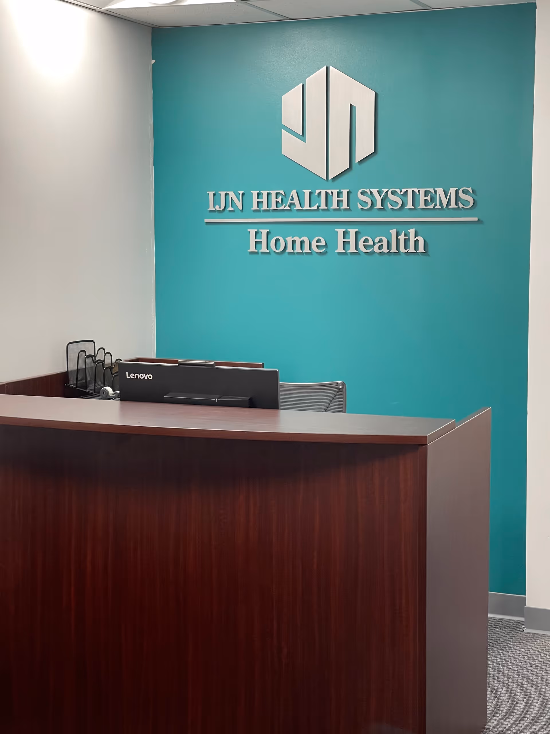 Reception desk in teal-walled lobby with LIN HEALTH SYSTEMS Home Health sign