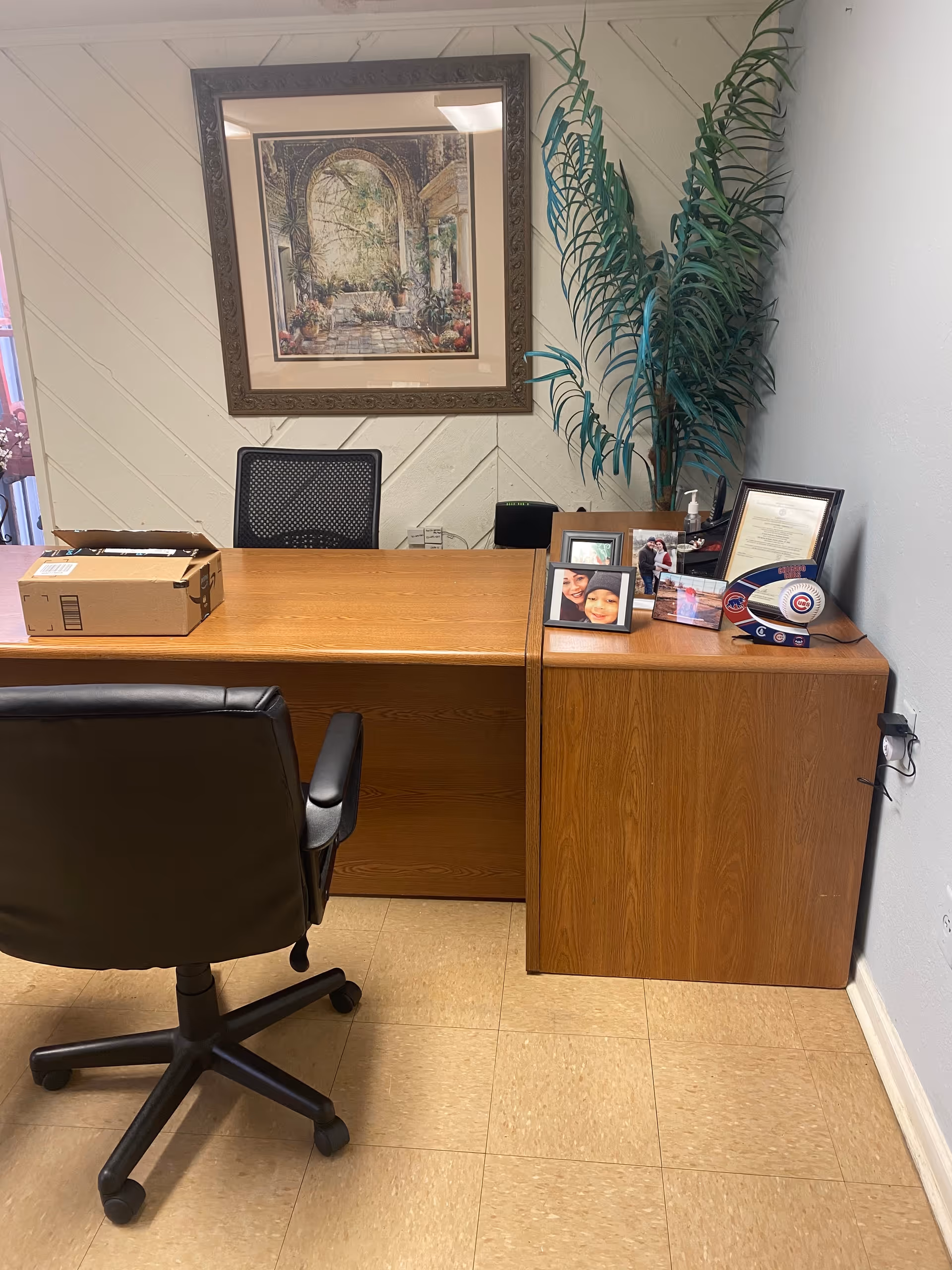 Reception desk with chair, plant, framed art, and photos in a care facility lobby.