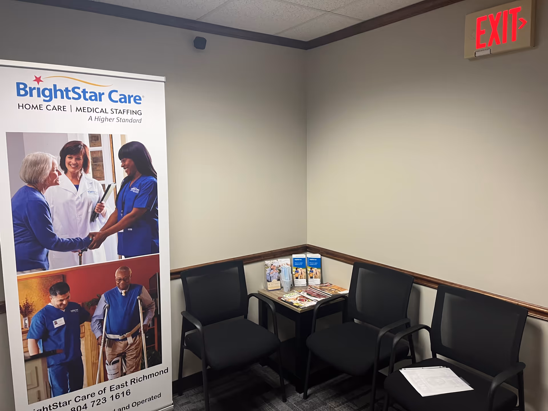 Interior waiting area with BrightStar Care banner, black chairs, magazine table, and exit sign.