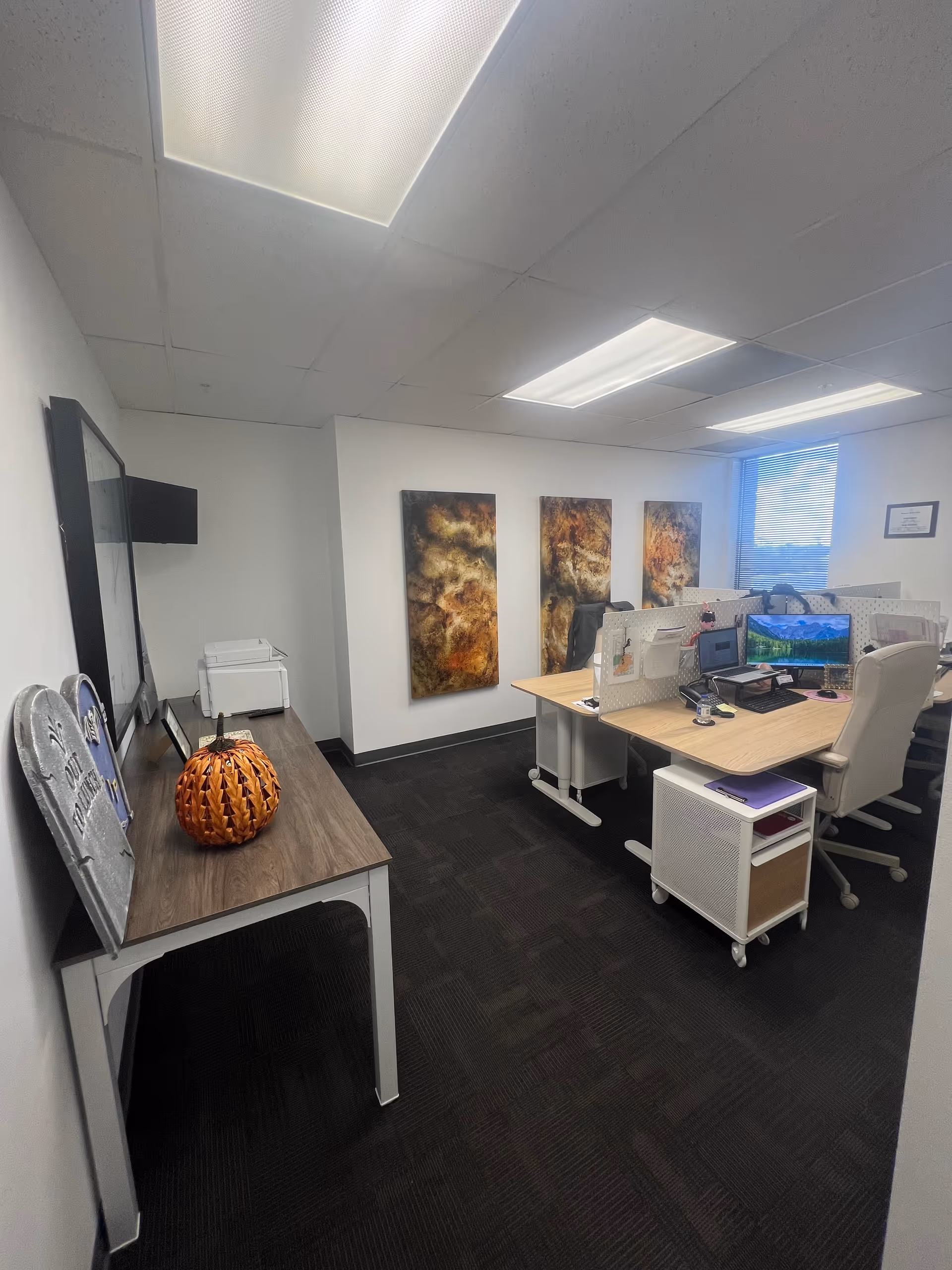 Office workspace with desks, computers, and wall art in a care facility.