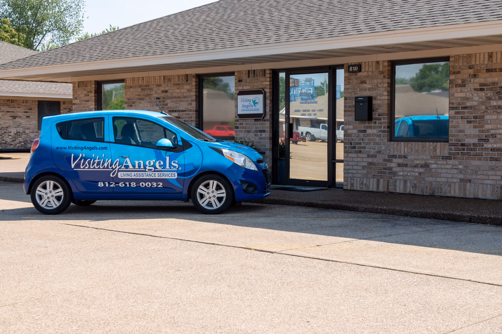 Blue Visiting Angels van parked in front of a brick senior home care facility