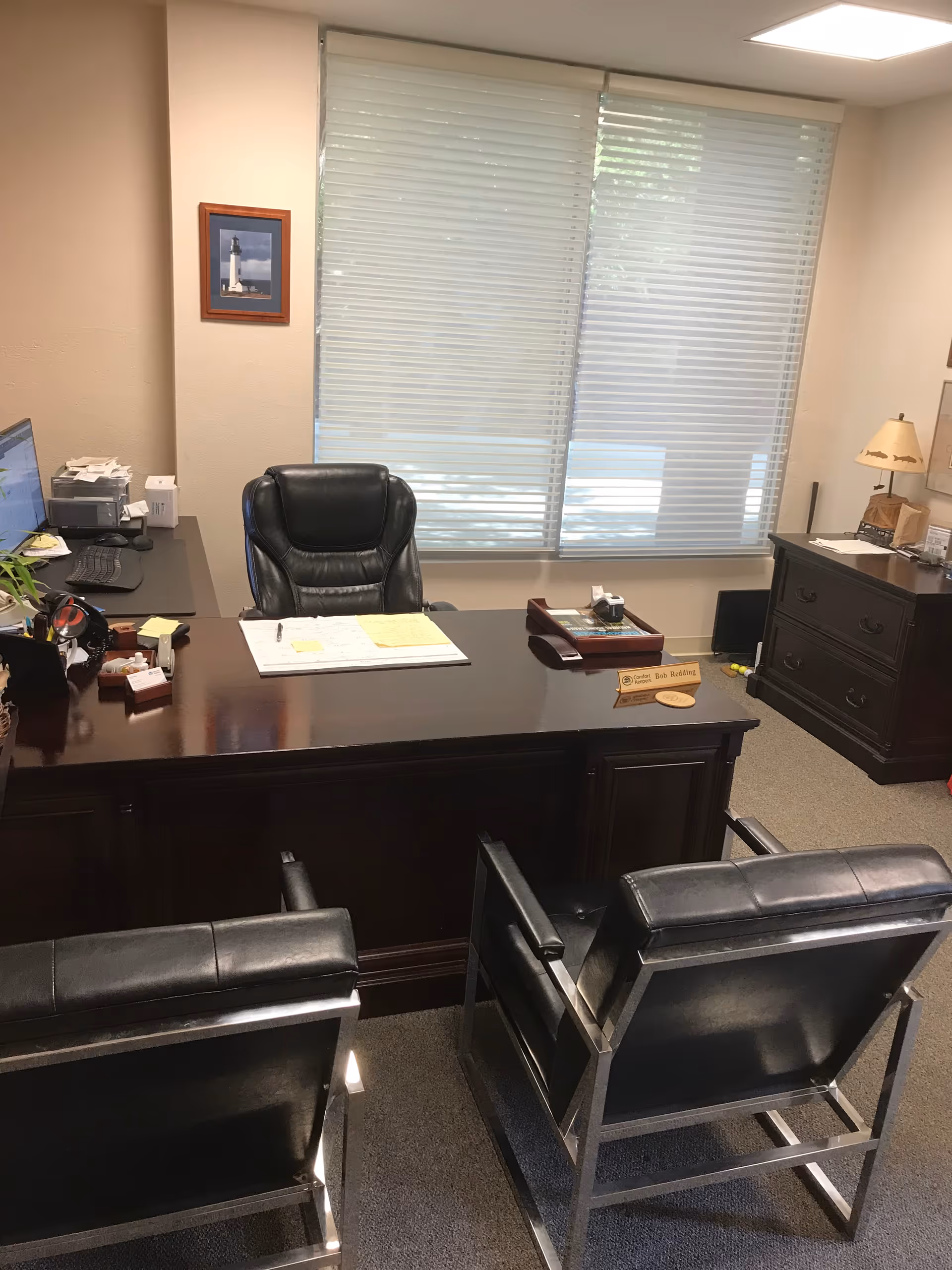 Dark wooden desk with chairs in a private office and window blinds