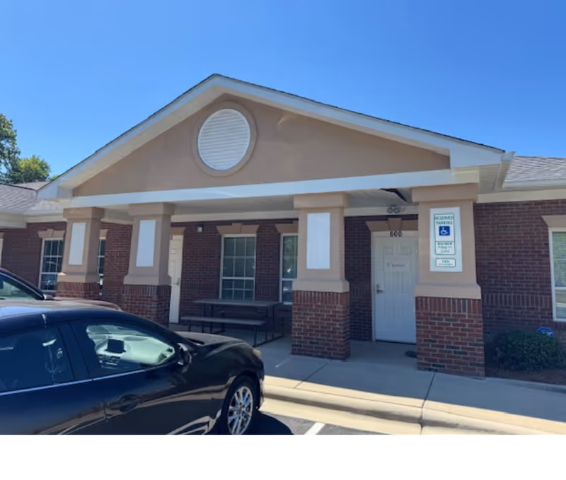 Front view of a BAYADA Pediatrics building entrance with brick columns and a parked car.