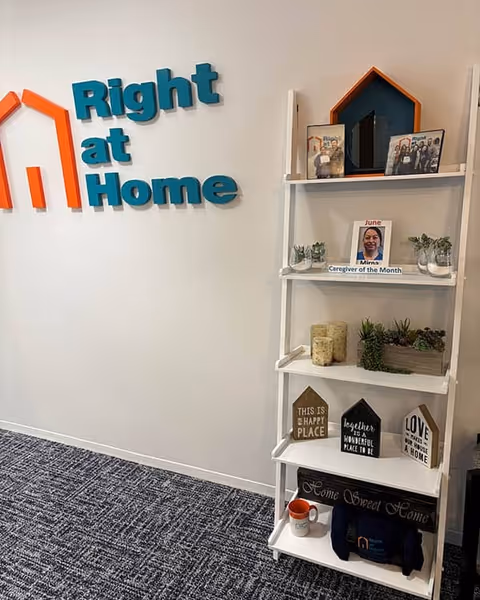 Interior of Right at Home facility showing logo wall and a white shelf with decor