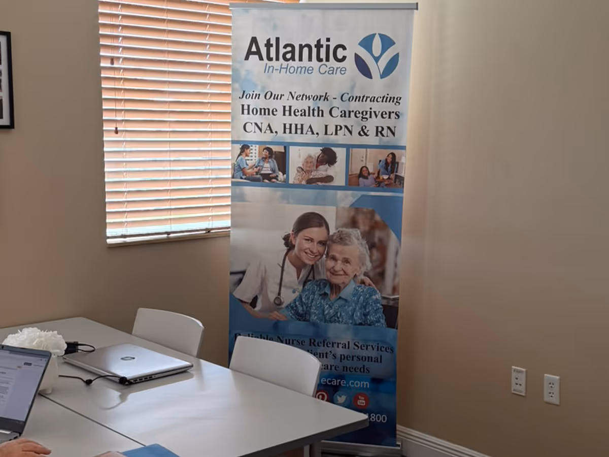 Conference room setup with an Atlantic In-Home Care banner beside a window and a table.