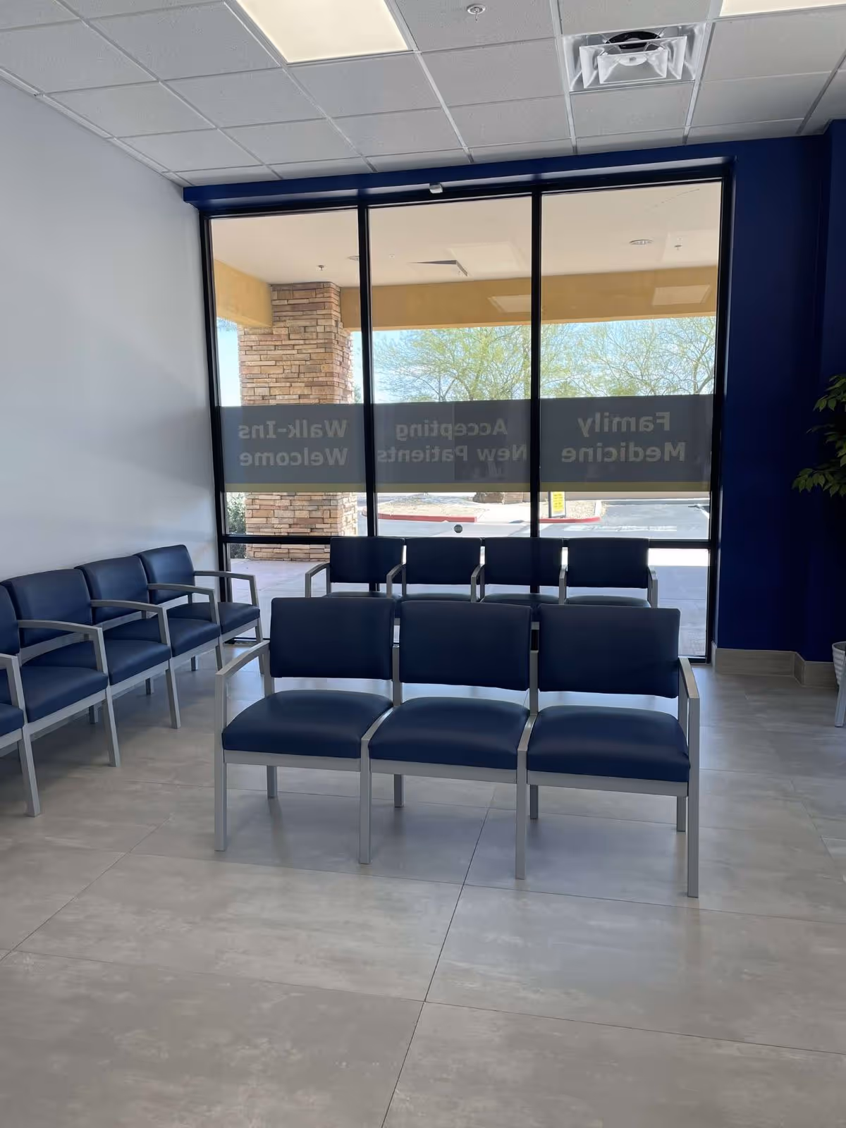 Interior waiting area with blue chairs and large glass windows at MY DR NOW