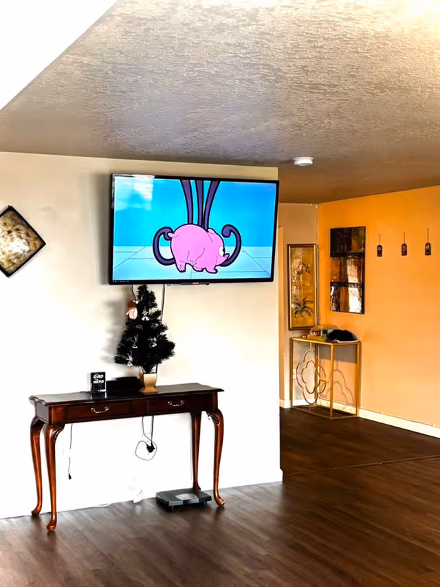 Cartoon elephant on wall-mounted TV above a wooden console in a cozy living area.