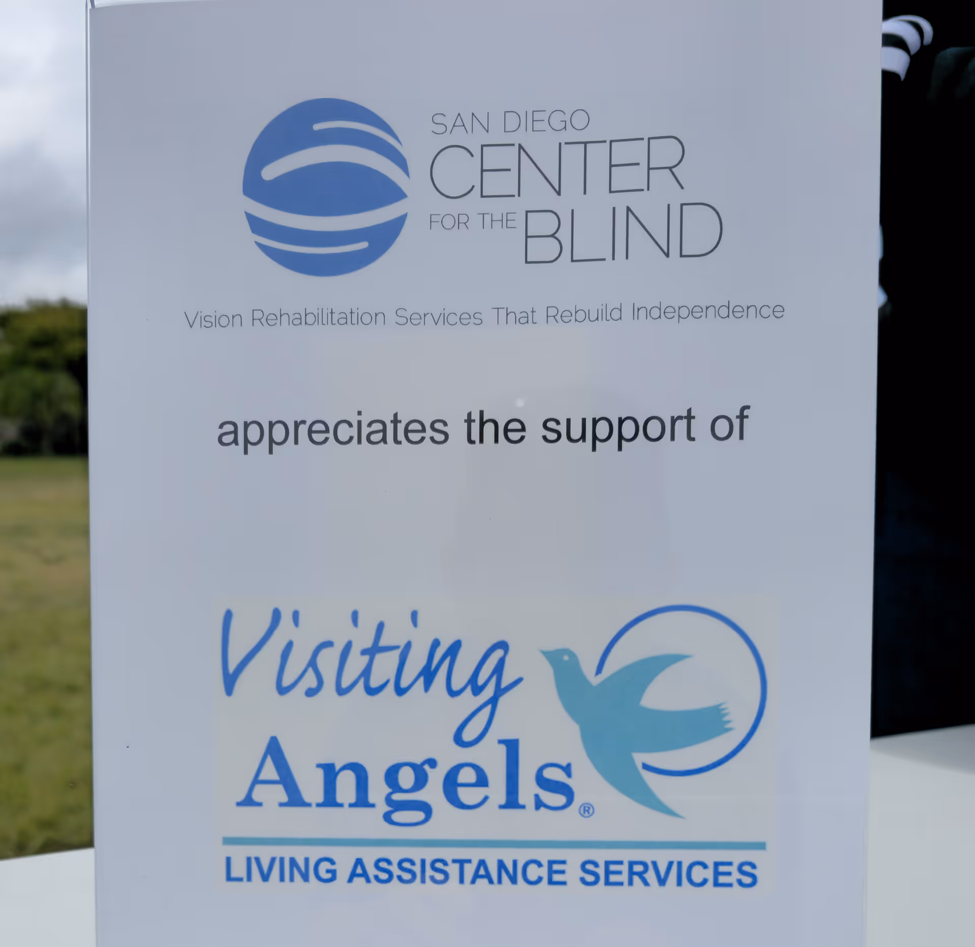 Outdoor sign displaying Visiting Angels Senior Home Care logos and Living Assistance Services text.