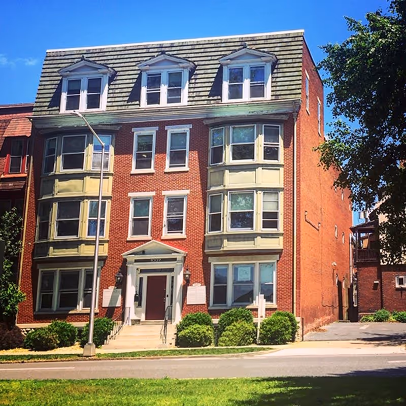 Red brick, three-story building with bay windows and a central front entrance.