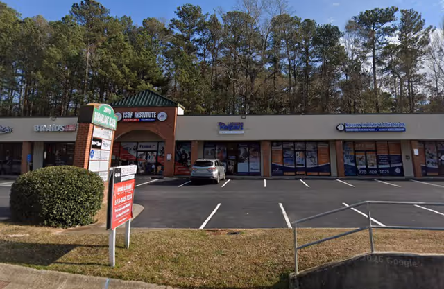 Exterior view of a strip mall with Senior Helpers storefront and parked cars