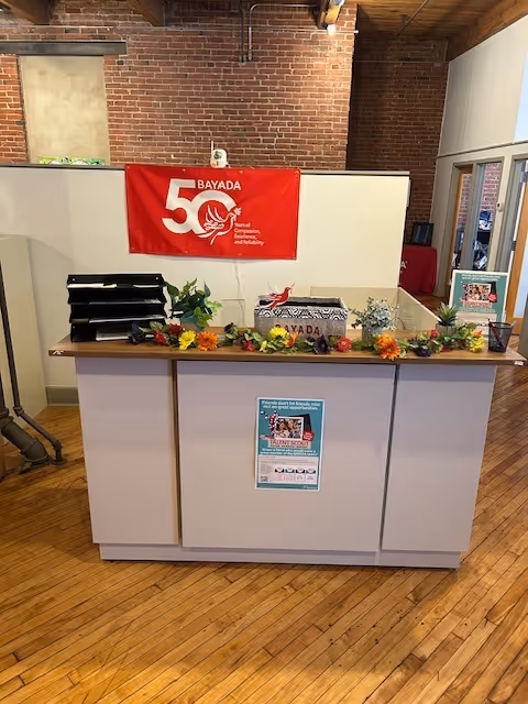 Indoor reception desk with a Bayada banner and floral garland.