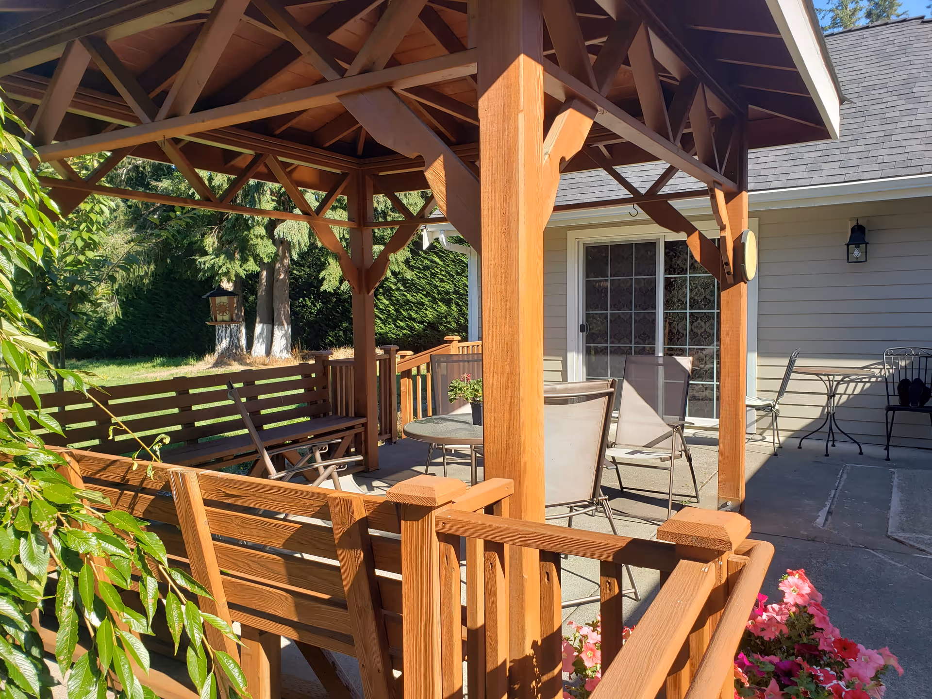 Outdoor wooden pergola patio with chairs and tables beside the house at Snoqualmie Valley Senior Care.