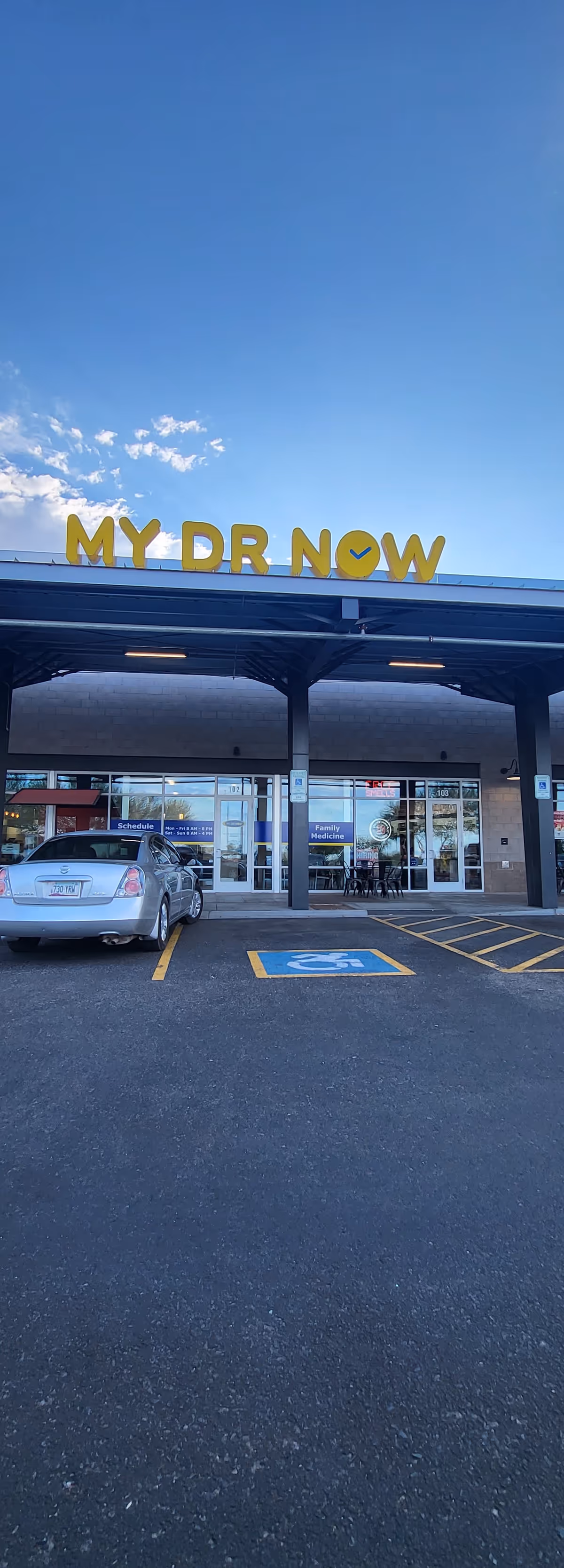 Front of a building with MY DR NOW sign, entrance doors, and handicap parking.