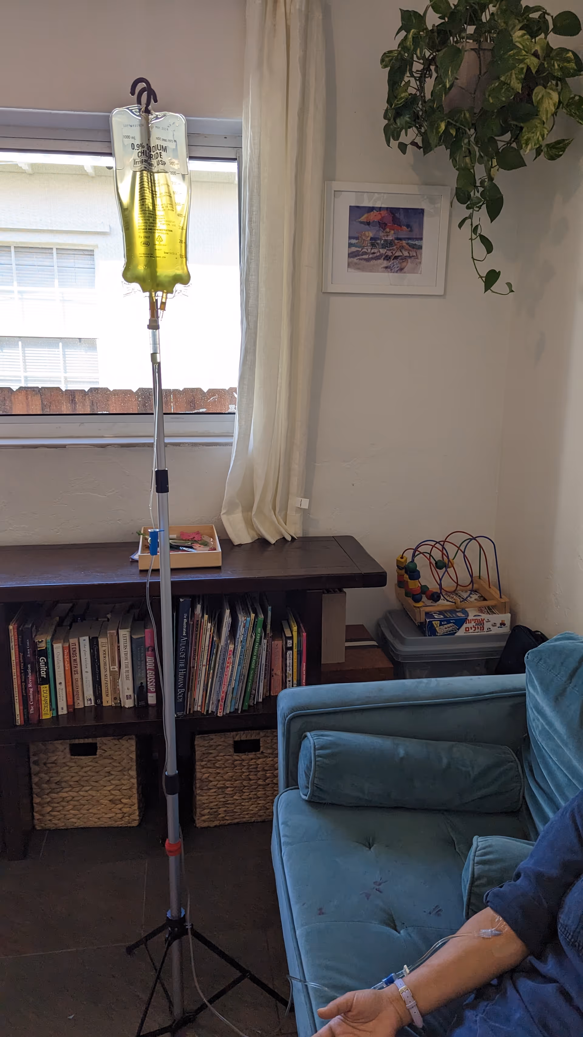 IV drip stand beside a blue sofa in a cozy living room at a senior facility.