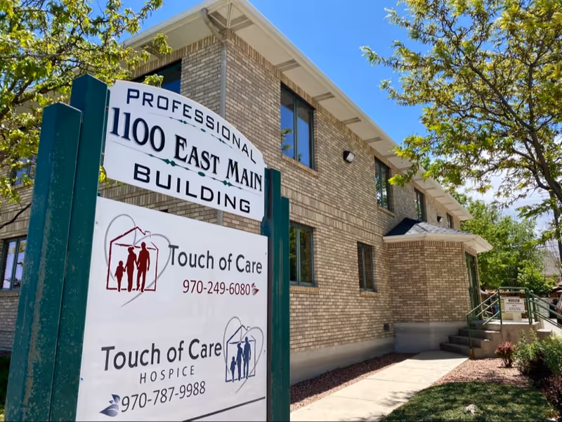 Exterior view of a brick senior living building with Touch of Care signage.
