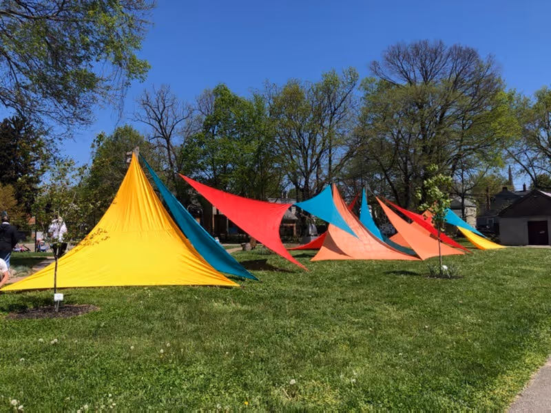 Colorful fabric tents form a bright outdoor display on a grassy park.