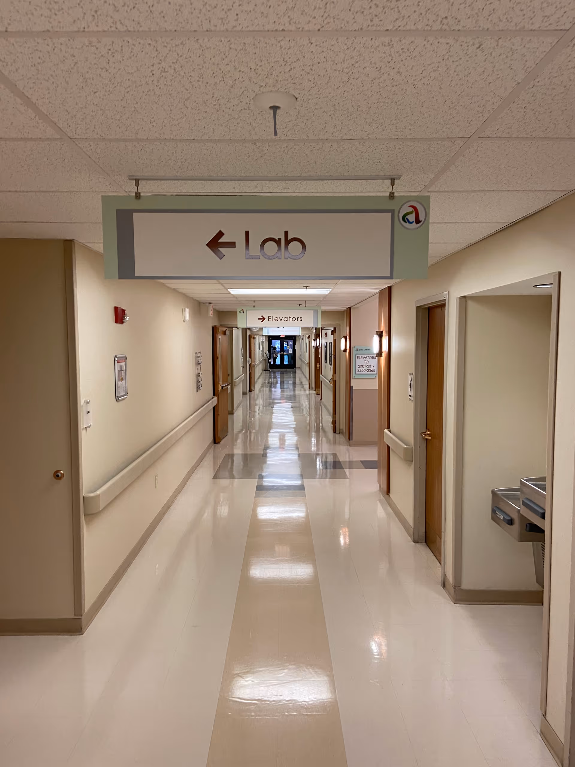Long interior hospital corridor with Lab and Elevators signs, clean, quiet, and well lit for visitors.