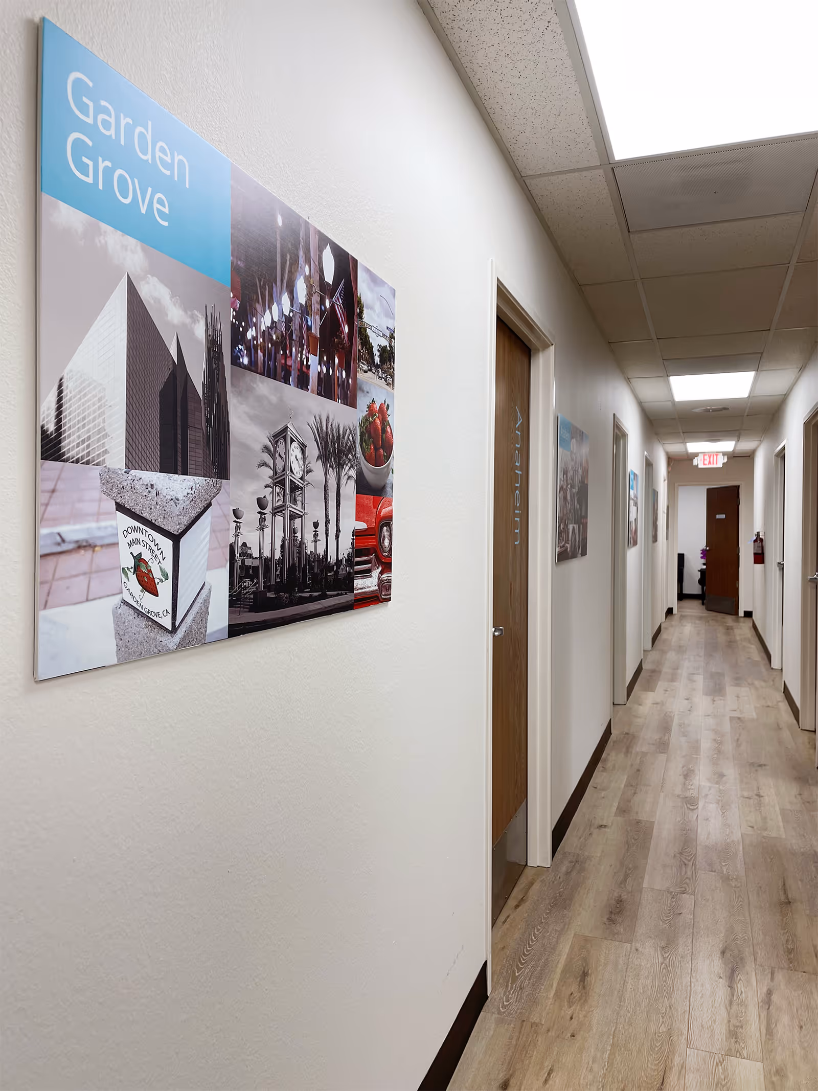 A clean hallway in a senior facility with wall art and wooden doors.