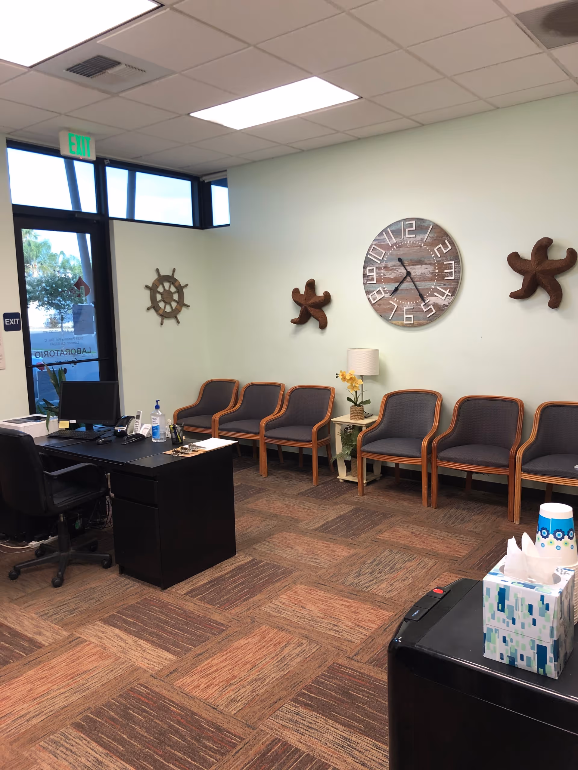 Office reception area with desk, row of chairs, and nautical wall decorations.