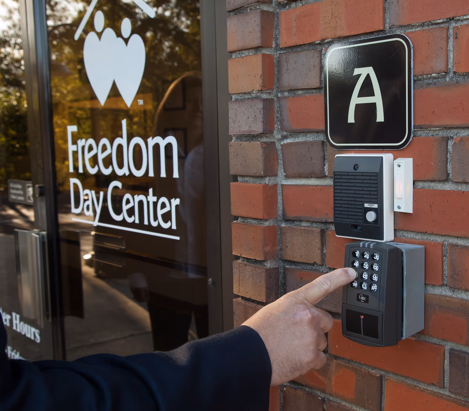 Close-up of brick building entrance with Freedom Day Center sign and security keypad.