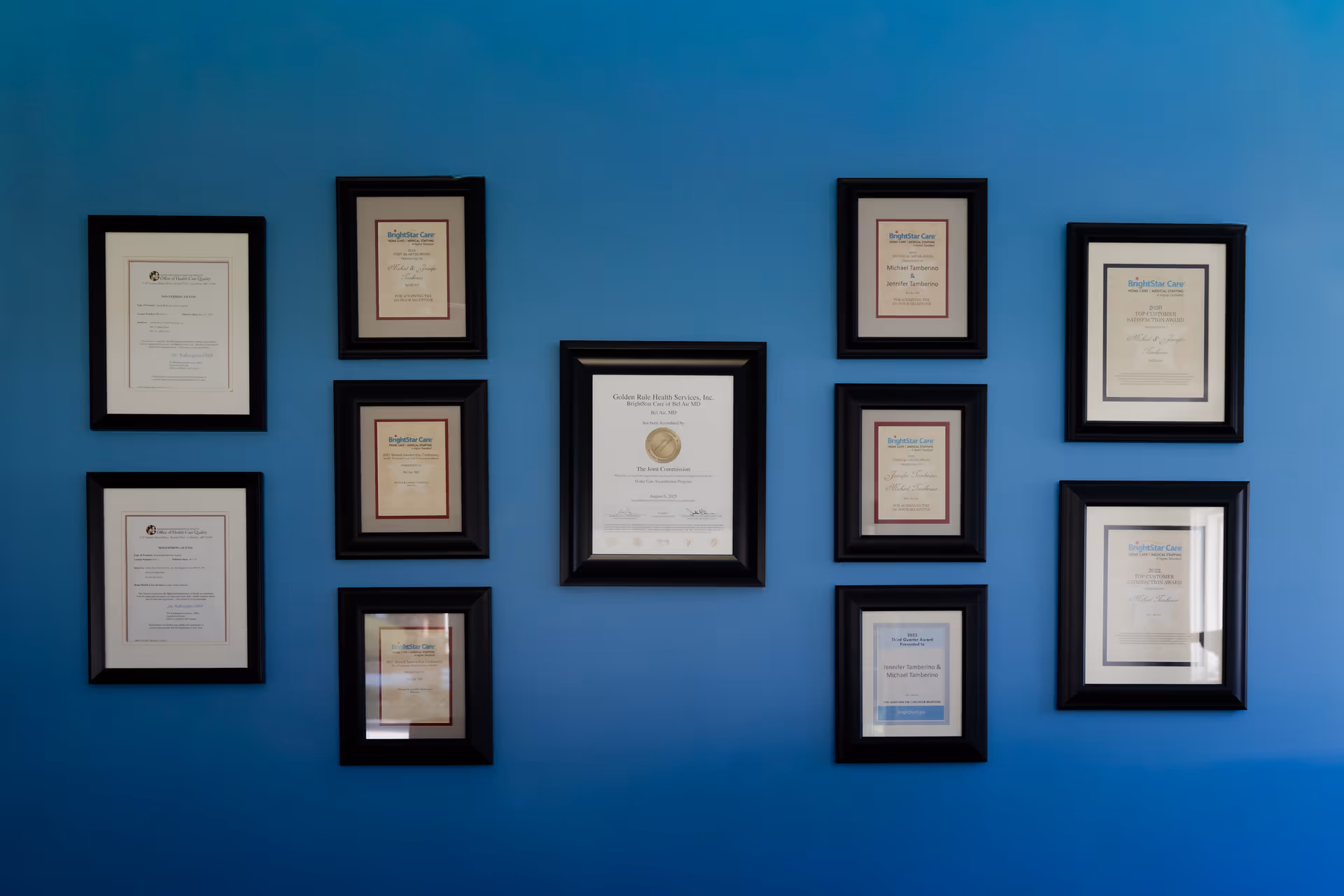 Blue wall displaying multiple framed certificates arranged in a grid.