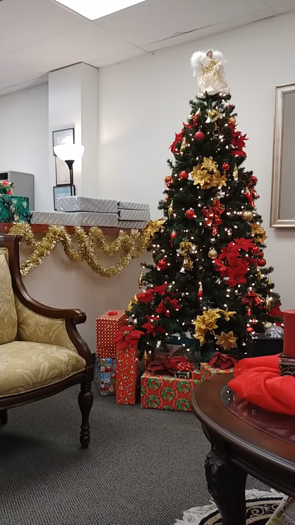 Decorated Christmas tree with wrapped gifts sits in a cozy lounge area.